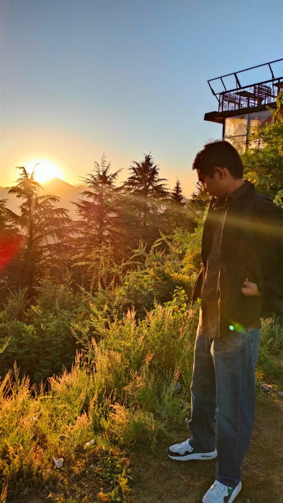 A person looking toward the setting sun over a mountain slope.