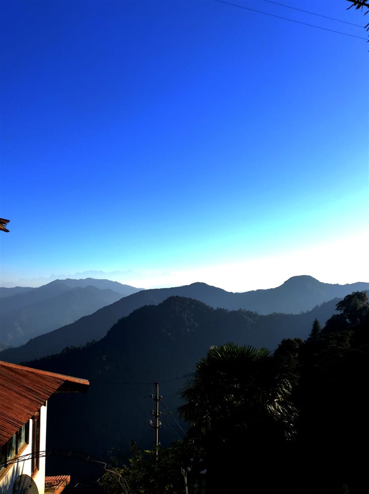 Blue mountain ridges receding beneath a clear sky.