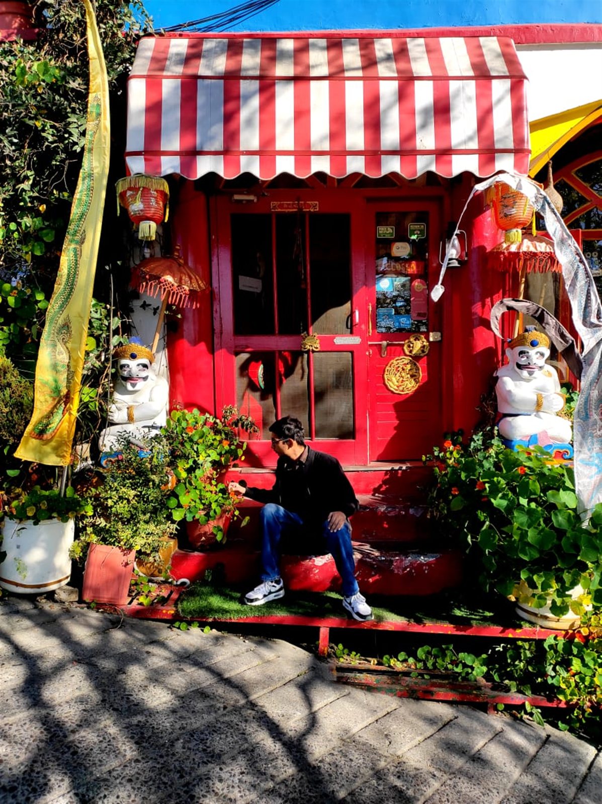 A red Tibetan-style storefront with striped awning and lanterns at Doma’s Inn.