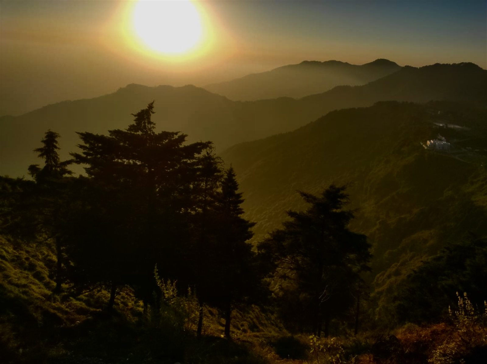 Golden sunlight above dark, forested mountain ridges.